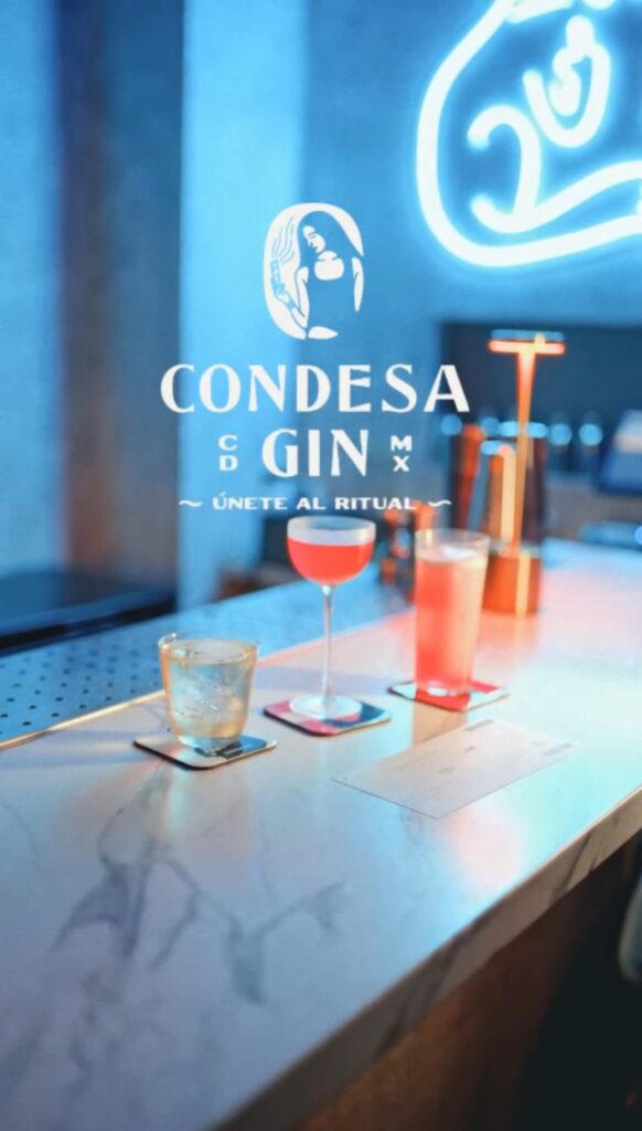 Los tres cócteles de Gato Negro × Condesa Gin en la barra, con el gato de neón al fondo
